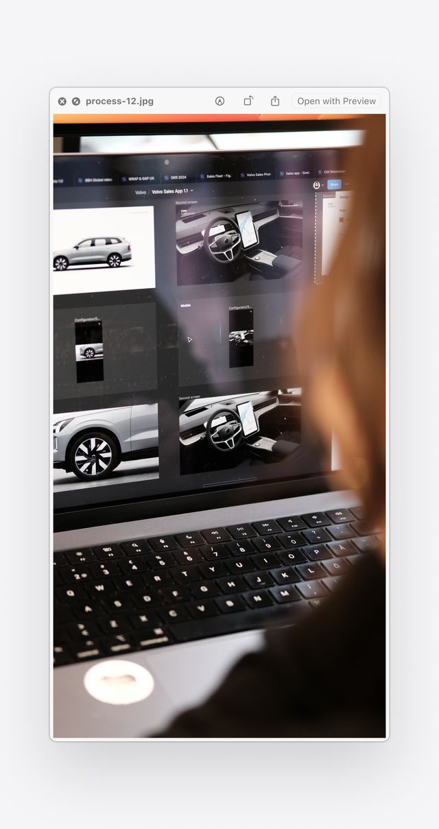 Close-up photo of a person working design mockups on a laptop screen, focusing on large screen experience for dealerships.
